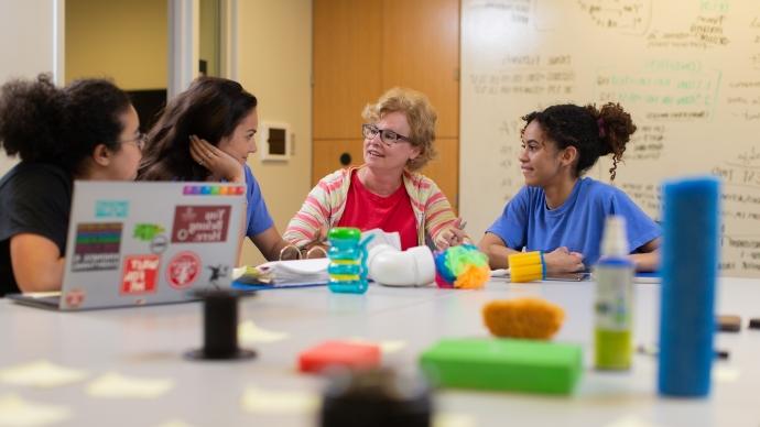 students sit with a professor in a psychology lab