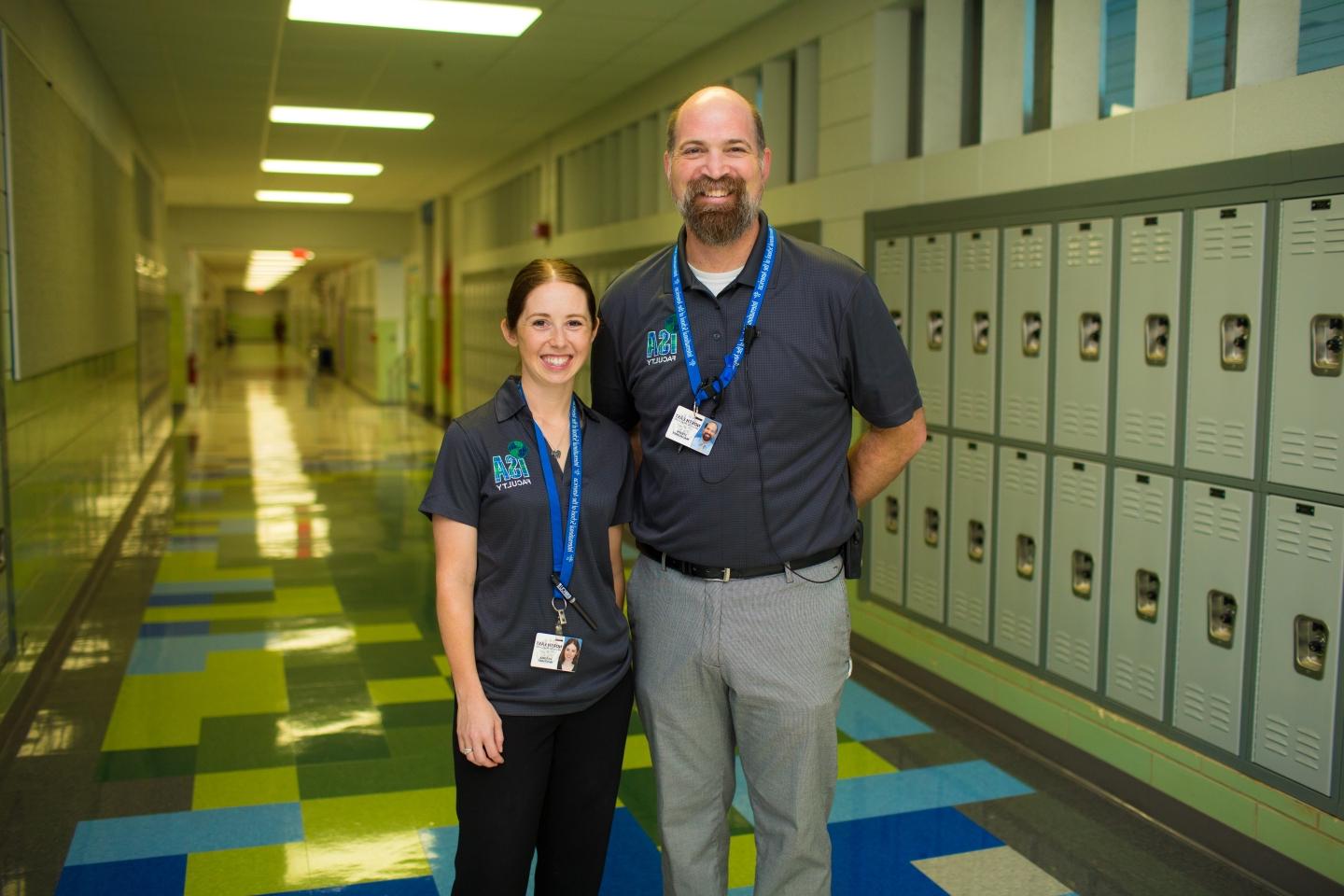 Professor and student stand together in a school hallway